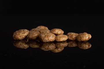 Lot of whole chocolate ball breakfast cereals heap isolated on black glass