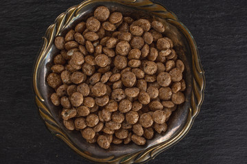 Lot of whole chocolate ball breakfast cereals in old iron bowl flatlay on grey stone