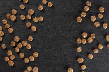 Fototapeta na wymiar Lot of whole chocolate ball breakfast cereals copyspace in middle flatlay on grey stone