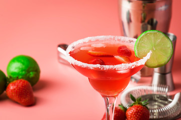 Strawberry red margarita alcoholic cocktail with tequila, liqueur, berries, lime juice, sugar and ice, pink background, copy space
