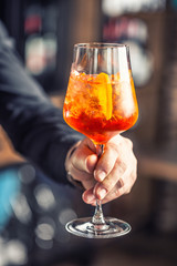 Aperol spritz drink. Bartender hand holding glass with  Aperol Spritz drink