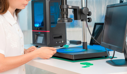 Woman worker in control of Resin LCD / DLP / SLA 3D Printer in technology lab