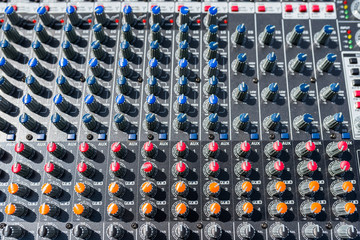 Close up photo of a professional sound mixer with many adjustments, knob switches and buttons of...