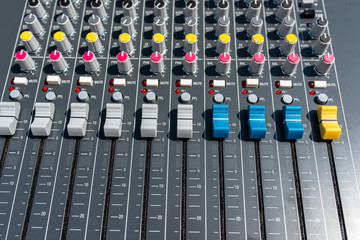 Close up photo of a professional sound mixer with many adjustments, knob switches and buttons of...