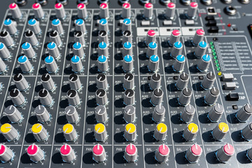 Close up photo of a professional sound mixer with many adjustments, knob switches and buttons of...