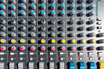 Close up photo of a professional sound mixer with many adjustments, knob switches and buttons of...
