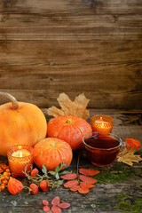 orange pumpkins, tea cup, autumn leaves and candles on rustic wooden background. fall season, thanksgiving holiday, Halloween concept. shallow depth, soft selective focus