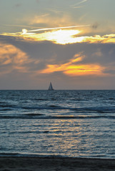 Sailboat from the evening beach at sunset time