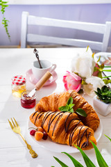 Breakfast on white wooden background - croissant, jam, berries and coffee