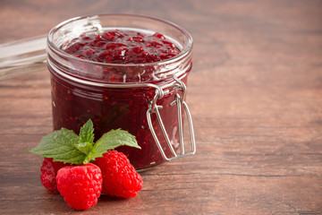 Jar of Raspberry Jam on a Rustic Wooden Table
