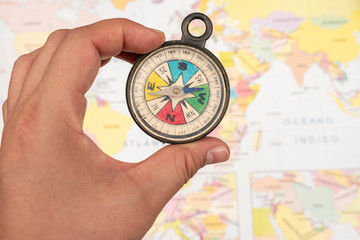 Woman hand holding a colorful compass with a map as background