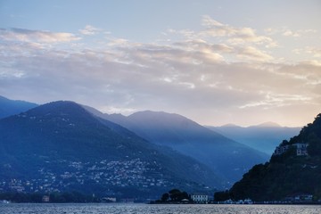 The sun rises over the Alps and Lake Como. View from the promenade of Como.