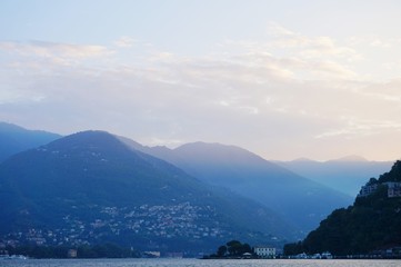 The sun rises over the Alps and Lake Como. View from the promenade of Como.