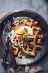 Belgian crispy waffles with fried egg, tomatoes and latte coffee on grey table
