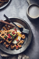 Belgian crispy waffles with fried egg, tomatoes and latte coffee on grey table