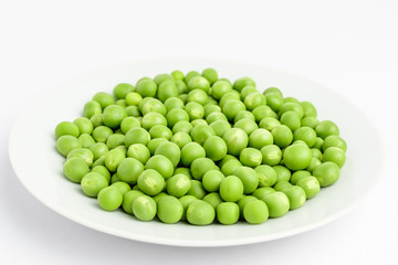 Fresh organic green peas on a white plate isolated on white, side view, with space for text
