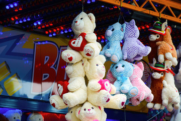 Hanging teddy bears and cuddly animal prizes in a stall on a funfair. Plush toy animals at the fairground.