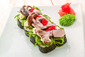 cooking, asian kitchen, sale and food concept - close up of hands with tongs taking sushi at street market Assorted of fresh sushi