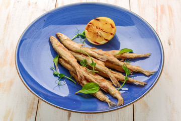 wooden board with smelt fried fish and salad