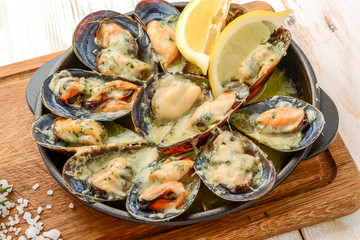 Delicious seafood mussels with with sauce and parsley. Lemon and baguette . Clams in the shells. Top view.