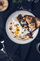 Poached eggs with runny egg yolk on a hummus with sautéed mushrooms, toasted bread anf herbs 