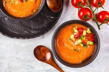 Traditional cold gazpacho tomato soup in black bowls on a gray background.