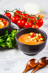 Traditional cold gazpacho tomato soup in black bowl on a gray background.