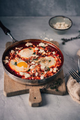 Spiced tomato Shakshouka in cast iron skillet. African cuisine breakfast