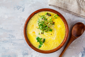 Vegan corn cream soup in wooden bowl on a gray background.