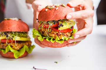 Cooking pink vegan burgers with beans cutlet, avocado and sprouts on white background.