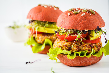 Pink vegan burgers with beans cutlet, avocado and sprouts on white background.
