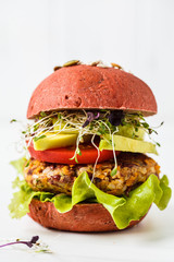 Pink vegan berger with beans cutlet, avocado and seedlings on white background.