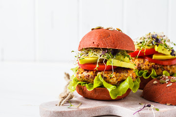 Pink vegan burgers with beans cutlet, avocado and sprouts on white background.