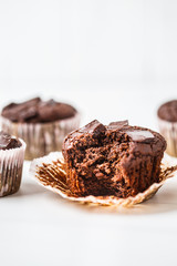 Chocolate vegan muffin in a paper cup on white background.