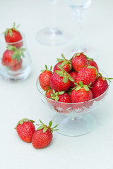 Fresh strawberries in glass bowl on white background