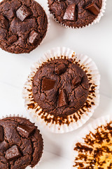 Chocolate vegan muffin in a paper cup on white background.