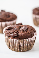 Chocolate vegan muffin in a paper cup on white background.