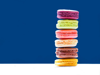 Macaron or Macaroon is sweet confection. French colorful macarons on blue background