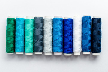Colourful blue spools of thread displayed vertically, isolated on white, top view