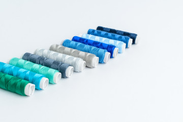 Colourful blue spools of thread displayed vertically, isolated on white, side view