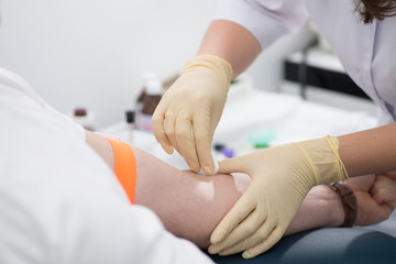 rubber nurse takes blood for analysis with a needle from the patient’s arms