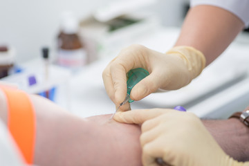 rubber nurse takes blood for analysis with a needle from the patient’s arms