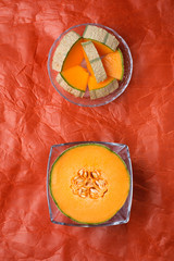 half and sliced cantaloupe melon around orange background. tasty sweet exotic fruit. flat lay
