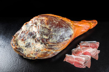 Traditionell spanischer Jamon Iberico Schinken Keule dry aged vom Duroc Schwein als closeup angeboten vor schwarzen Hintergrund 