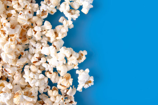 Close-up of fresh warm popcorn on blue background. Copy space for text