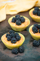 Homemade cupcakes or muffins with berries blackberries on bark background. Fresh berries and sweet pastries.