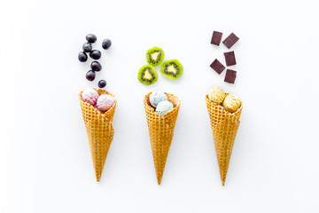ice cream in waffle cones, kiwi, chocolate on white backgroung top view