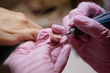 Woman in salon receiving manicure by nail beautician,manicurist uses a manicure nail file to process the nail plate and nail file