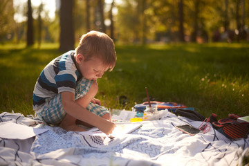 a boy of five to six years old draws in nature