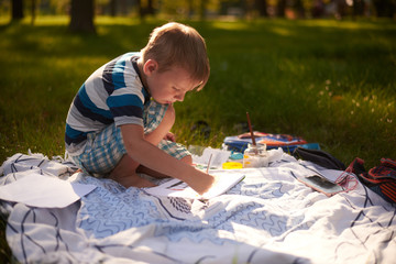a boy of five to six years old draws in nature